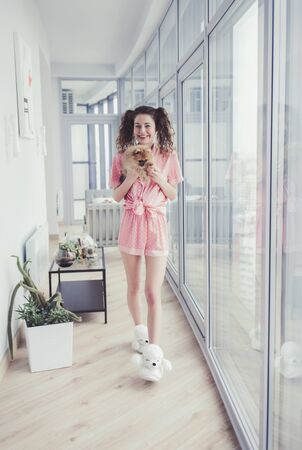 beautiful girl in home clothes holds a fluffy dog Spitz in her handsの写真素材