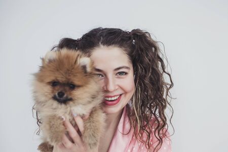 happy curly woman and fluffy dog spitz indoorの写真素材
