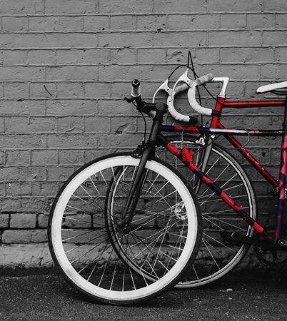 two vintage bicycles parking against red brick wallの写真素材