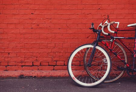 two vintage bicycles parking against red brick wall. copy spaceの写真素材