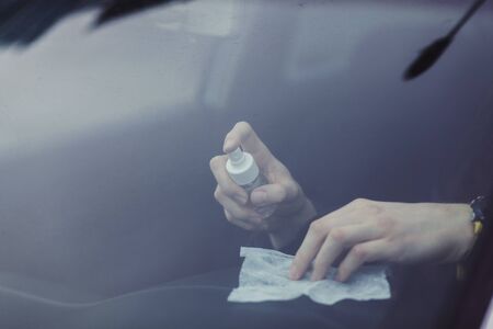 the driver cleans the car interior with an alcohol-based antibacterial spray. protection against the spread of coronovirus infectionの写真素材