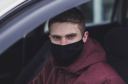 a man driving a car in black protective mask during an epidemic, a taxi driver in a mask, protection from coronavirusの写真素材