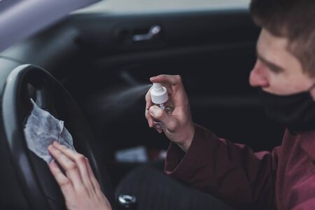 Man spraying anti-bacterial sanitizer spray in car. Sanitizer to prevent coronavirus, Covid-19.の写真素材