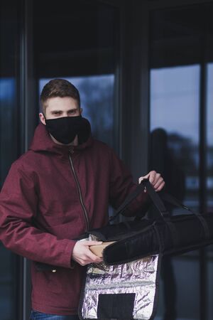 Delivery man holding bag with food in mask. Fast and free Delivery transport . Online shopping and Express delivery . Quarantineの写真素材