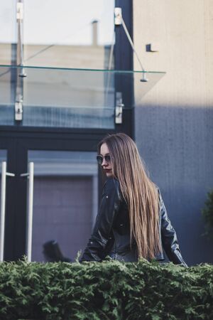 elegant woman in sunglasses and leather jacket on the streetの写真素材