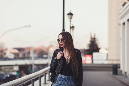 Glamour lady in leather jacket walking in city streetsの写真素材