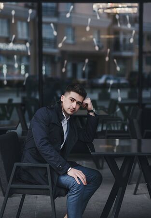 Young successful businessman is sitting at a table in a cafe near the officeの写真素材