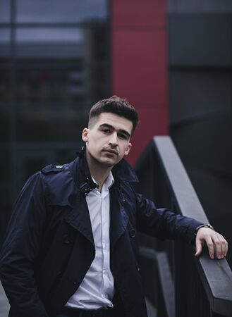 Handsome young man in suit and coat posing in cityの写真素材