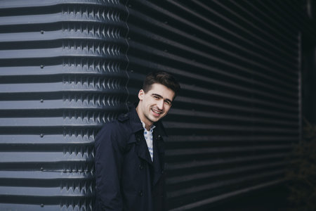 Young man wearing jacket and smile against wall
