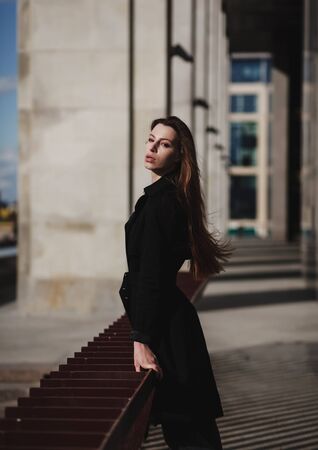 portrait of fashion girl in black coat in city.の写真素材