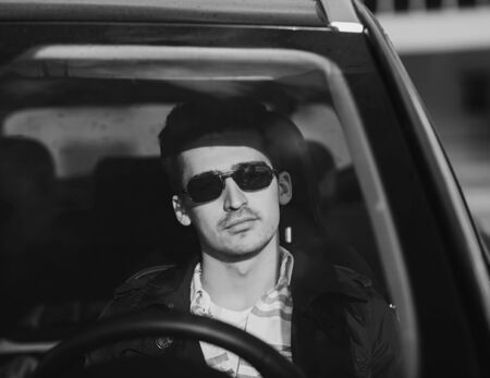 Handsome elegant man drives a car. black and white imageの写真素材