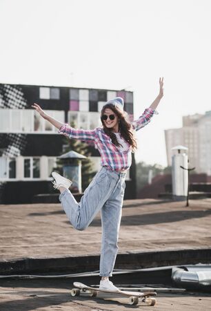 Beautiful young hipster girl riding on longboard in the cityscapeの写真素材