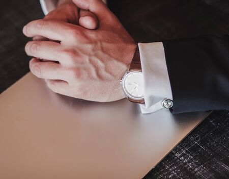hands of a business man in a watch. jacket, cufflinks, laptop-men's setの写真素材