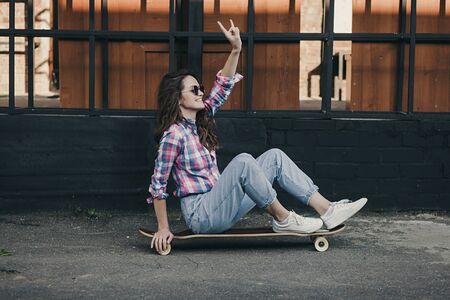Beautiful and fashion young woman sitting on skateboardの写真素材