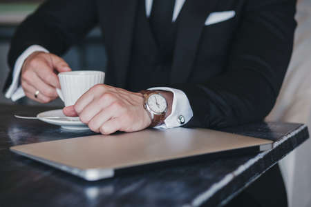 successful man in a suit in a cafe. Business concept. Digital tablet and cup of coffee on desk.の写真素材