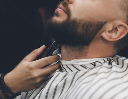 Barber makes beards correction in barbershop salon.の写真素材