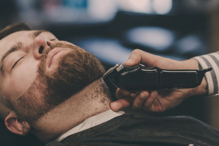 professional barber cuts a man's beard in the salon. shave and a haircutの写真素材