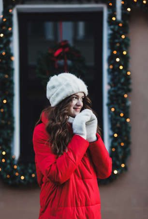 Beautiful woman winter portrait. Smiling girl wearing warm red coat and warm mittensの写真素材