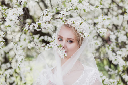 Beauty bride in bridal gown with bouquet and lace veil on the nature.の写真素材