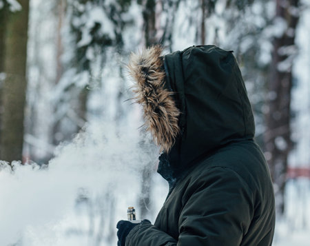 Stylish young man smoking electronic cigarette outdoor. Man vaping.