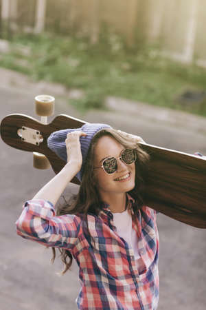 A girl in hat lies on skateboard, longboard. In summer in city on background of an asphalt roadの写真素材