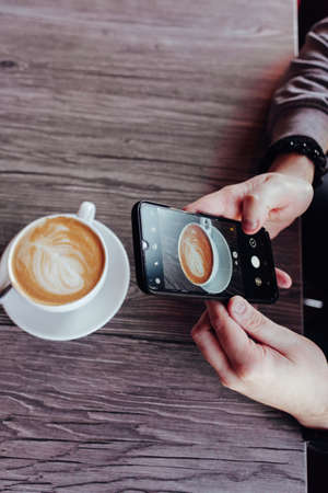 sugar cubes with tongs on a wooden background. cappuccino cup in the cafeの写真素材