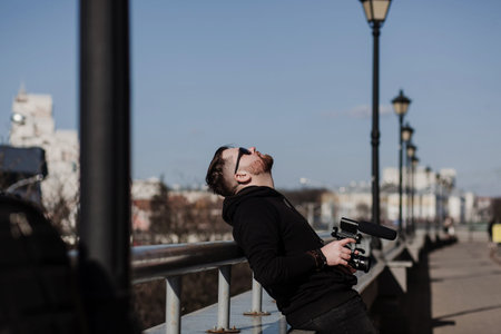 bearded man with a camera rests in the city after workの写真素材