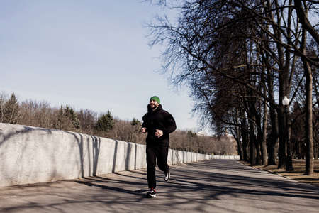 Young fit man stretching out his arms stretches outdoors against the background of the riverの写真素材