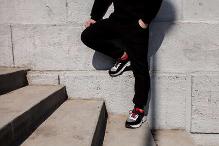 Portrait of handsome stylish urban man wearing black black hoodie and sneakers. Copy space. Advertising concept.の写真素材