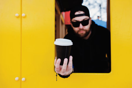 Funny man in a cap and sunglasses smiles against a yellow wall