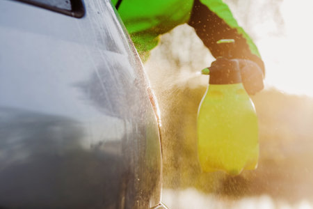 A man washes his car with a high-pressure water jet and brushes the windowsの写真素材