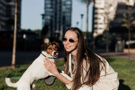 Young woman playing with terrier dog outdoors in the park.の写真素材