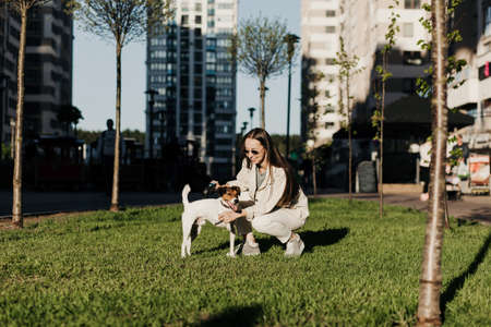 Young woman playing with terrier dog outdoors in the park.の写真素材