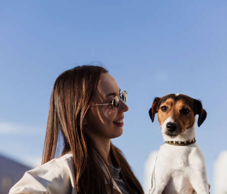 Young woman playing with terrier dog outdoors in the park.の写真素材