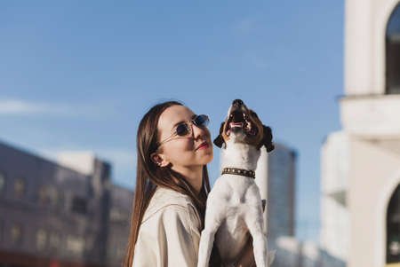 Young woman playing with terrier dog outdoors in the park.の写真素材