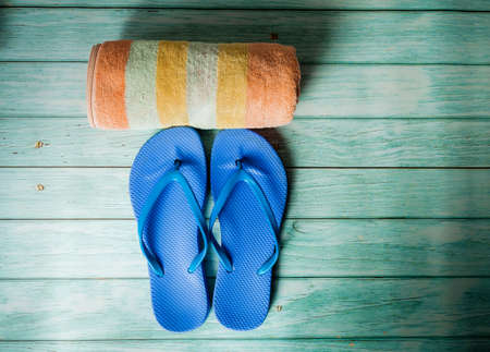Beach accessories on blue wooden floor. Top view. Towel and flip flopsの写真素材