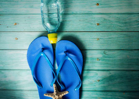 Beach accessories on blue wooden floor. Top view. Towel and flip flopsの写真素材