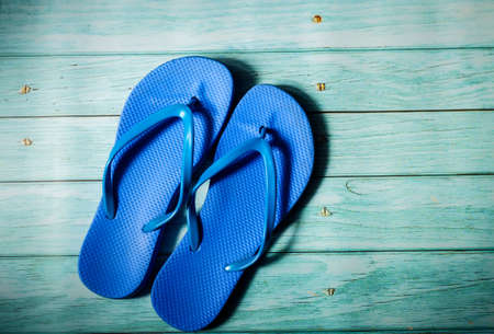 Beach accessories on blue wooden floor. Top view. Towel and flip flopsの写真素材