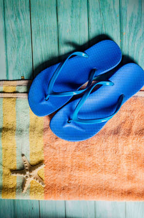 Beach accessories on blue wooden floor. Top view. Towel and flip flopsの写真素材