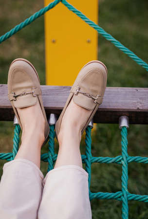 fashion outfit details. fashionable woman wearing pants and loafers lying on hammockの写真素材