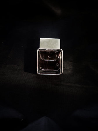 black fragrance perfume bottle on wood background. Top view.