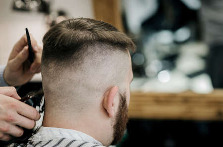 Barber trim hair with clipper on man in barbershop. Professional hairdresser cut hair with electric shearer machine on guy. black and white photoの写真素材