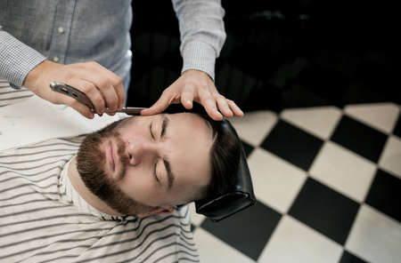 barber shaving a man with a sharp steel razor.の写真素材