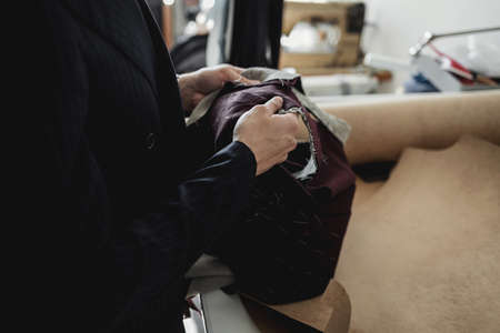 man tailor working on new clothing. hands with scissors in the workshopの写真素材