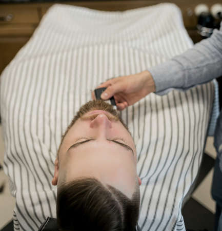 male client getting haircut at barber shop from professional hairstylist.の写真素材
