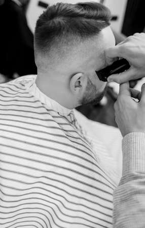 male client getting haircut at barber shop from professional hairstylist.の写真素材