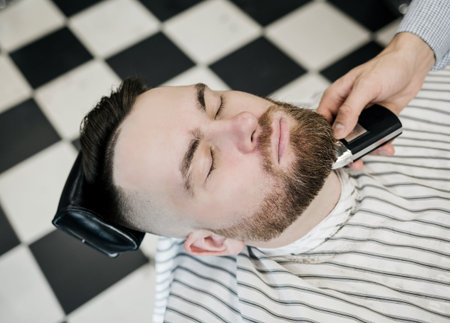 male client getting haircut at barber shop from professional hairstylist.