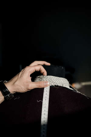 modern tailor measuring back length of bespoke suit during model fitting in atelier studioの写真素材
