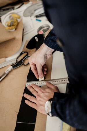 modern tailor measuring back length of bespoke suit during model fitting in atelier studio