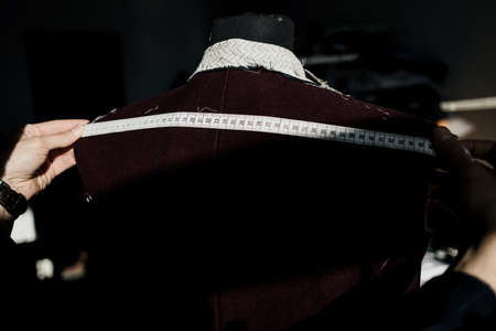 modern tailor measuring back length of bespoke suit during model fitting in atelier studioの写真素材